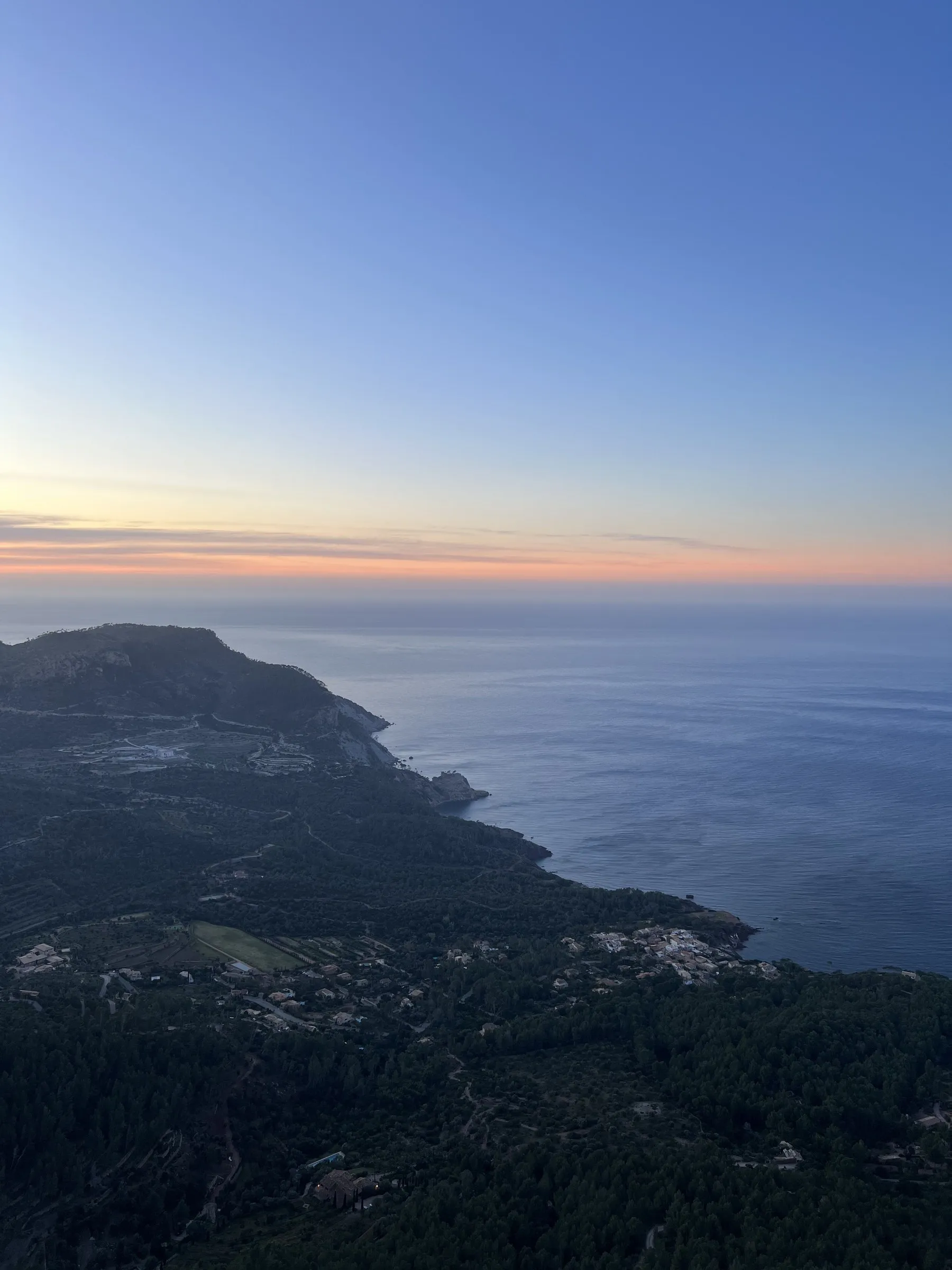 Die Küste von Banyalbufar bei Sonnenuntergang, mit Terrassen, die zum Meer hin abfallen.