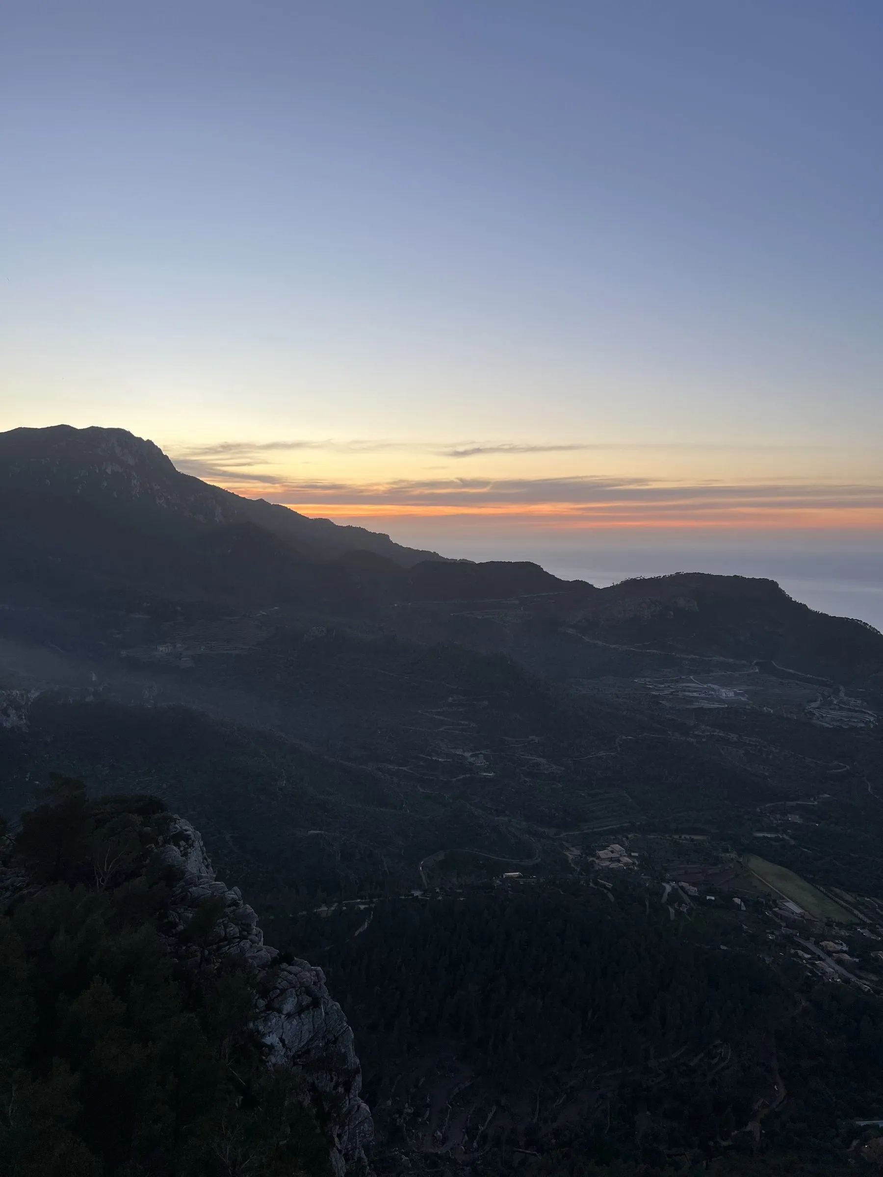 Die Silhouette des Gebirges vor dem letzten orangefarbenen Streifen am Horizont über dem Meer.