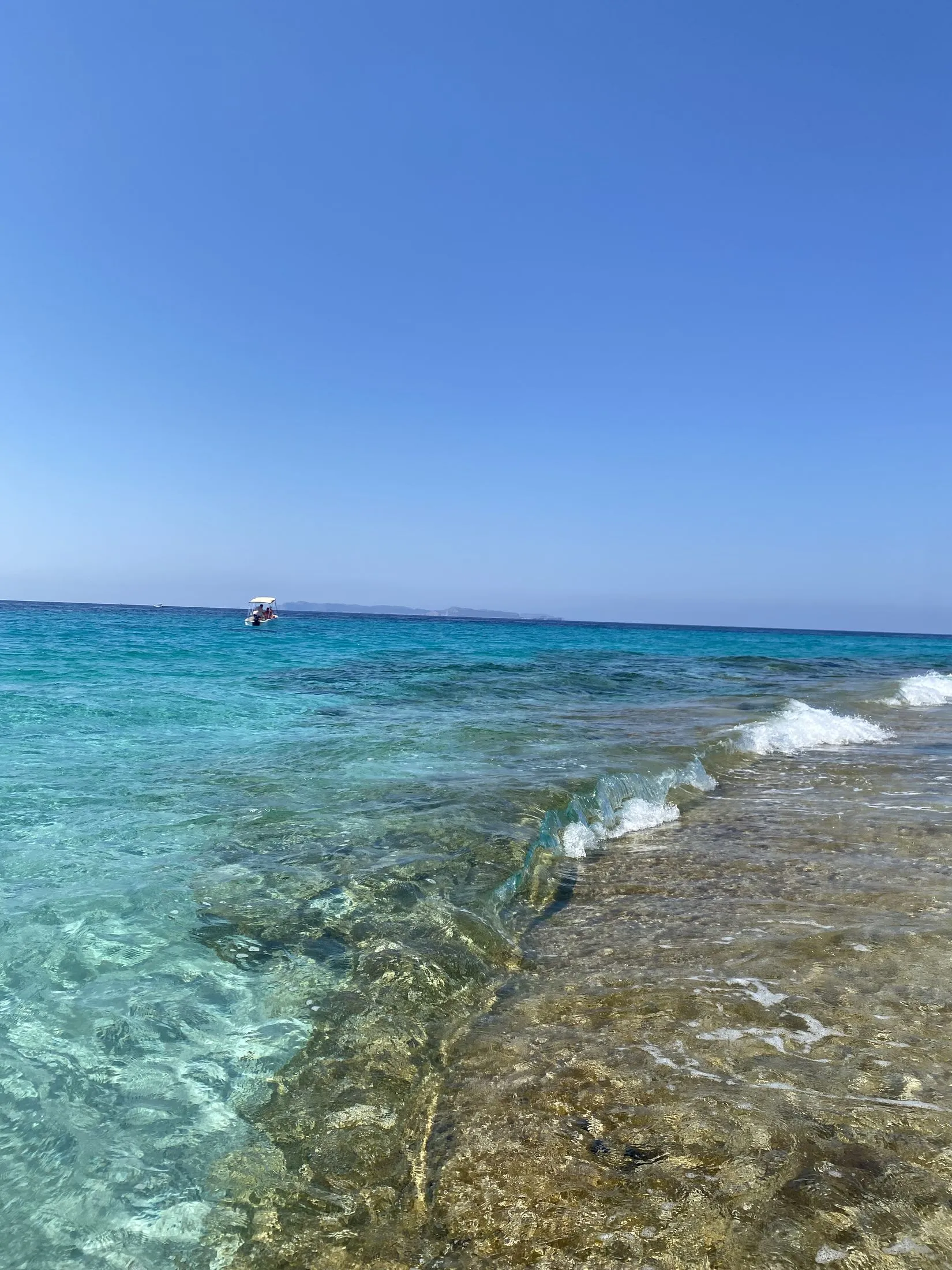 Die Felsküste am Cap de ses Salines mit türkisfarbenem, klarem Wasser über den Steinen.