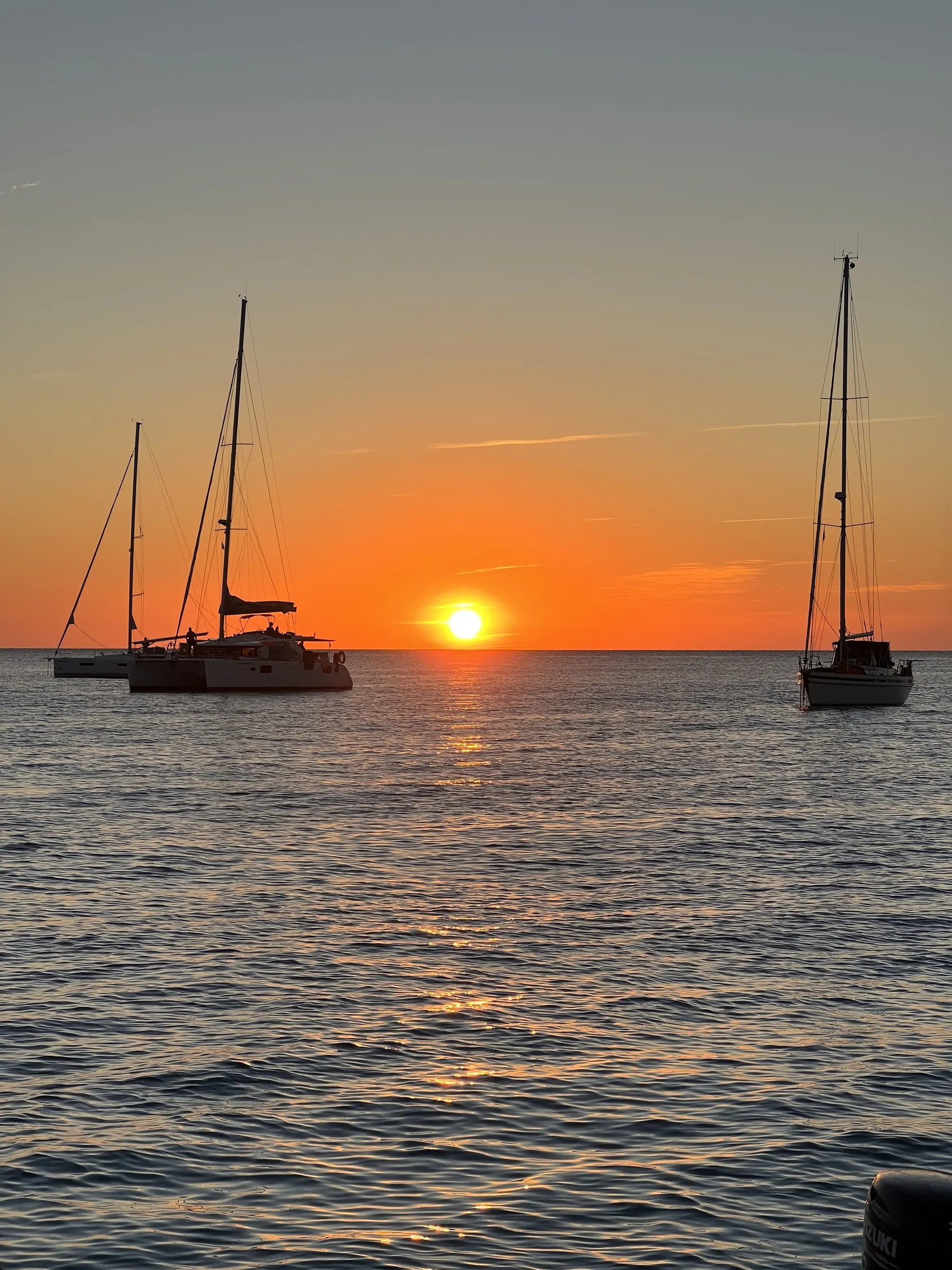 Twee voor anker liggende zeilboten als silhouet tegen de ondergaande zon bij Cap de ses Salines.